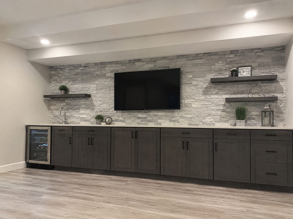 Basement cabinetry run with a stone feature wall and floating shelves