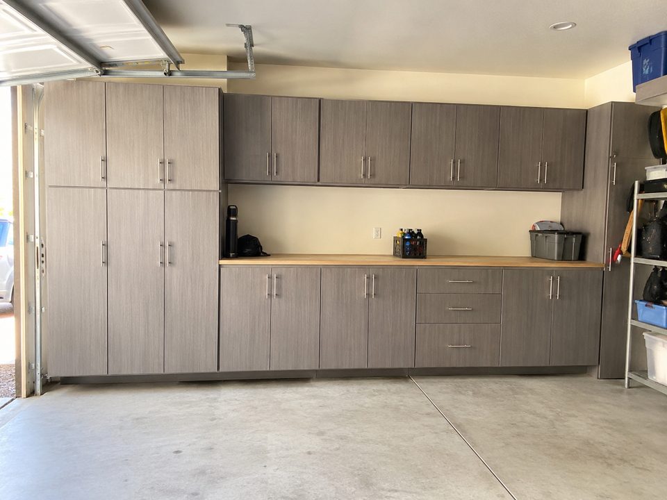Garage cabinet system with wall-hung upper cabinets and a full-length workbench