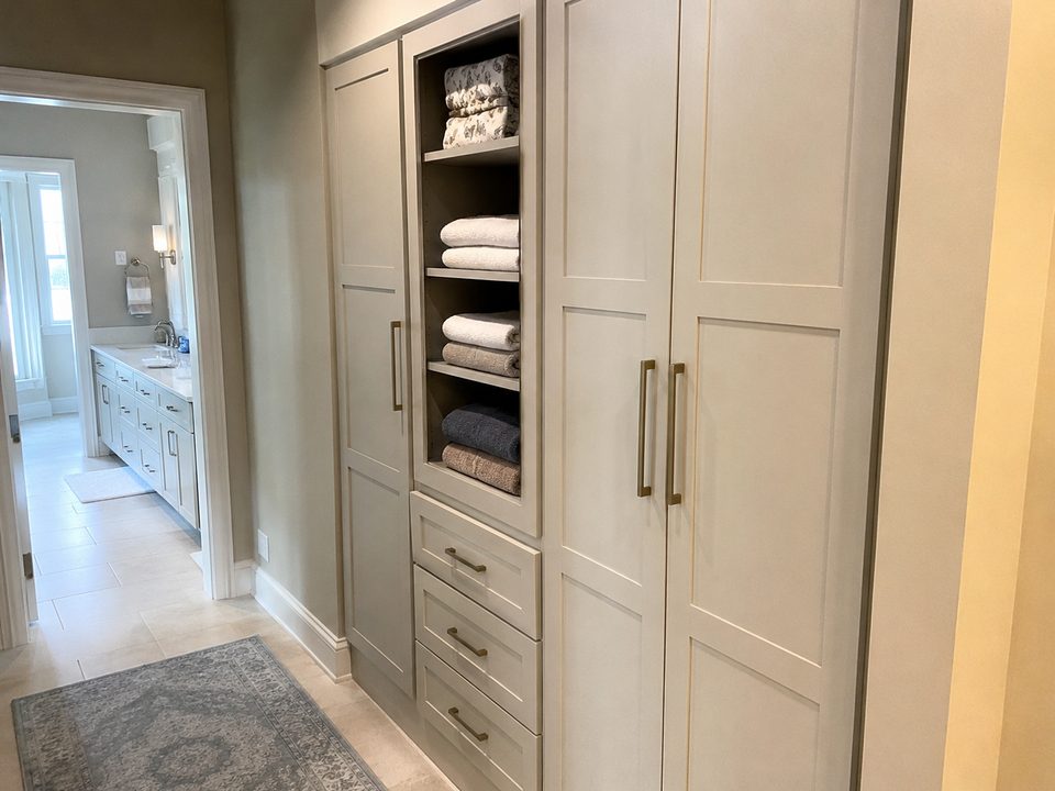 Bathroom linen tower with open shelving above a drawer bank