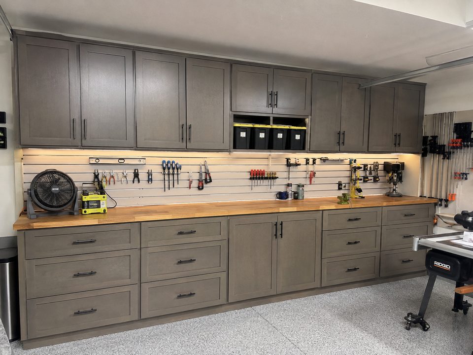 Workshop cabinets with a butcher block bench top, pegboard tool wall, and drawer storage